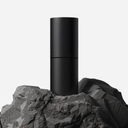 Black cylindrical object on a rocky surface with a white background