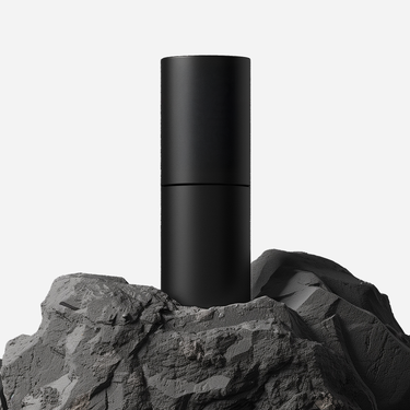 Black cylindrical object on a rocky surface with a white background